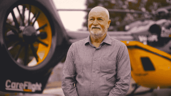 portrait of a senior man standing next to a car